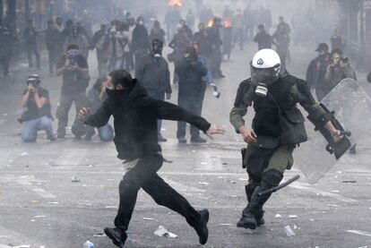 Un policía antidisturbios corre detrás de un manifestante cerca del ministerio de Finanzas en Atenas.
