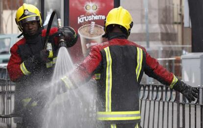 Bomberos refrescan sus uniformes en la mañana de hoy tras finalizar los trabajos de extinción