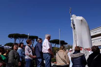 Un grupo de personas rezan ante la estatua de Juan Pablo II situada frente al hospital Gemelli de Roma, este miércoles.