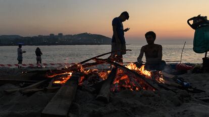 Varios vecinos preparan una hoguera durante la noche de San Juan de 2023 en la playa de Riazor (A Coruña).