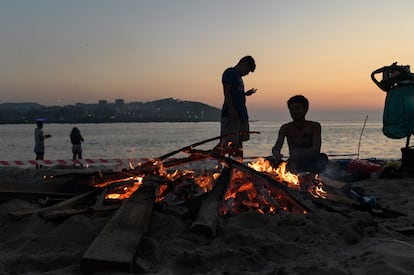 Varios vecinos preparan una hoguera durante la noche de San Juan de 2023 en la playa de Riazor (A Coruña).