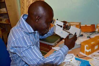 El señor Jalloh examina las lentes en su microscópio.