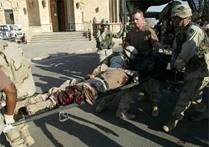 Médicos militares transportan ayer a un herido en la explosión de una bomba en las proximidades de un palacio de Sadam en Tikrit.