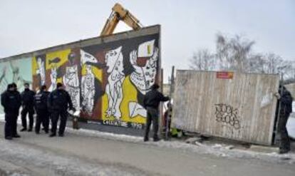 Policías vigilan mientras una máquina excavadora trabaja en la polémica obra de construcción de un edificio de apartamentos justo al lado de una sección del antiguo Muro de Berlín, en Alemania, hoy, miércoles 27 de marzo de 2013.