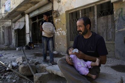 Un hombre alimenta a su hija a la puerta de su casa, que ha sido parcialmente destruida en Azaz, a las afueras de Alepo, Siria. Agosto de 2012.