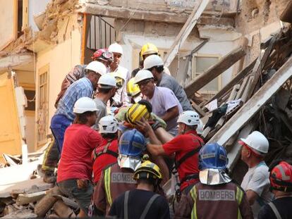 Los bomberos y técnicos rescatando a la mujer atrapada bajo los escombros del edificio derrumbado de Lleida.