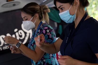 Dos enfermeras preparan dosis de la vacuna contra la covid-19 para inmunizar adultos mayores y trabajadores de recolección de basuras, considerados como grupo prioritario, en un puesto de vacunación móvil diseñado para descongestionar los centros de salud hoy, en la comuna de La Reina, en Santiago (Chile). 
