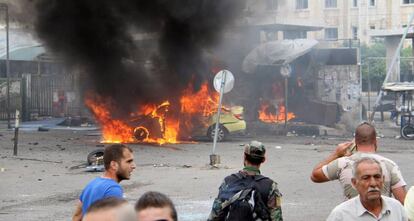 Un soldat sirià i diversos civils davant d'un cotxe que ha explotat aquest dilluns a Tartous.