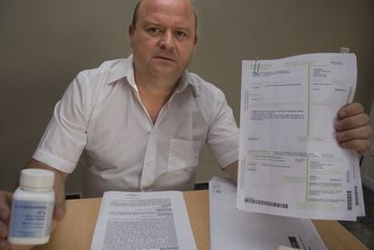 Javier Ferrándiz holds up his prescriptions and drugs.