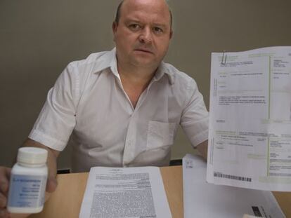 Javier Ferr&aacute;ndiz holds up his prescriptions and drugs.