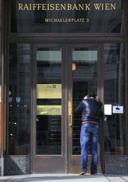 Un hombre mira por la puerta de un banco en Viena.