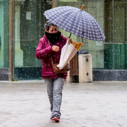 TERUEL, 14/03/2025.- Una mujer se protege del frío una ligera nevada que cae esta mañana en Teruel. La Agencia Estatal de Meteorología (Aemet) mantiene activada este viernes la alerta amarilla por acumuaciones de nieve en 24 horas en el Pirineo y la provincia de Teruel. EFE/Antonio Garcia