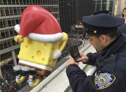 La seguridad es máxima en Nueva York, donde el popular desfile de Acción de Gracias de la cadena comercial Macy's reúne hoy a unos tres millones de personas en las calles de la ciudad. En la imagen, un oficial de policía de Nueva York toma una foto con su móvil.