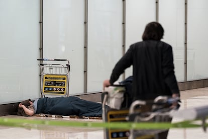 Una persona sin hogar duerme en la Terminal 4 del Aeropuerto Adolfo Suárez Madrid-Barajas.