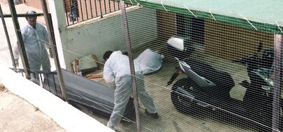 Agentes judiciales introducen en el féretro los restos del hombre descuartizado en Villanueva del Río (Sevilla).