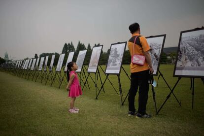 Una niña escucha las explicaciones de su abuelo durante una exhibición de fotografías de la Guerra de Corea en el Cementerio Nacional de Seúl (Corea del Sur), en su 64º aniversario.