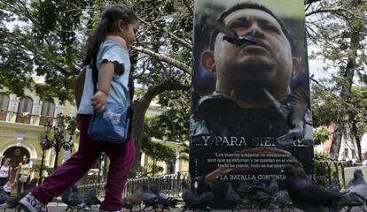 Una niña corre frente a un retrato del fallecido Hugo Chávez.