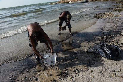 Dos hombres trabajan en una playa afectada por el derrame de crudo, en Campeche, el 26 de julio.