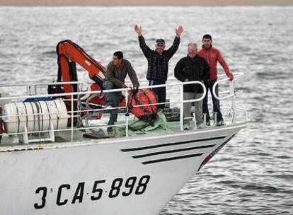 Los pescadores saludan desde uno de los barcos tras salir rumbo a Tánger.