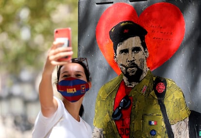 Una mujer se toma una fotografía con el grafiti de Messi vestido como el Che Guevara.