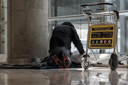 Una persona sin hogar se prepara para dormir en la T4 del aeropuerto Adolfo Suárez-Madrid Barajas, el 12 de mayo.