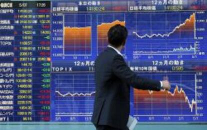 Un viandante pasea por delante de un panel de cotizaciones en Tokio.