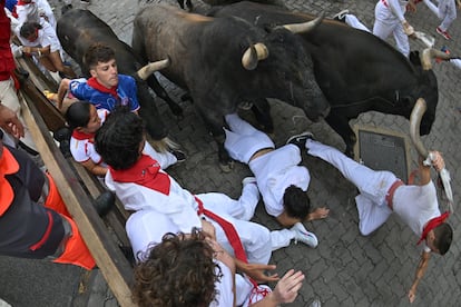 Dos mozos caen al paso de los toros de la ganadería sevillana de Miura durante el octavo y último encierro, este lunes.