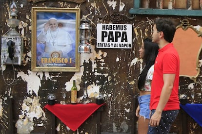 Turistas caminan frente a un cartel alusivo al papa Francisco en Cartagena (Colombia). El papa Francisco estará en Colombia del 6 al 10 de septiembre para recorrer las ciudades de Bogotá, Villavicencio, Medellín y Cartagena.
