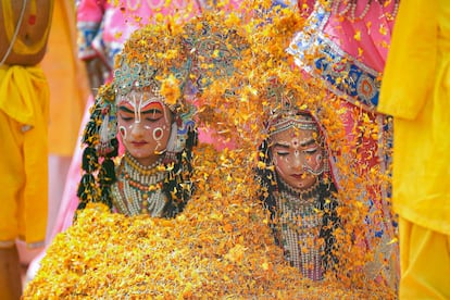 Dos mujeres, vestidas como diosas hindús, son cubiertas con flores durante el festival Holi en Vrindavan, la India, el martes.