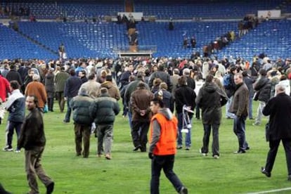 Algunos espectadores evacuan el Bernabéu desde el césped.