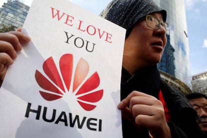 Un manifestante muestra un cartel en apoyo a Huawei.