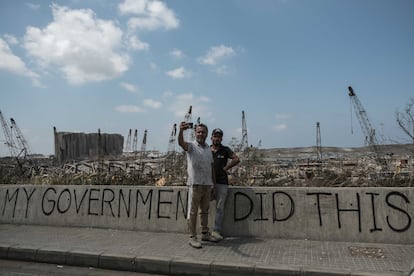 Dos libaneses el pasado mes de septiembre frente a los restos calcinados del puerto de Beirut donde se lee una pintada:'Mi Gobierno hizo esto'.