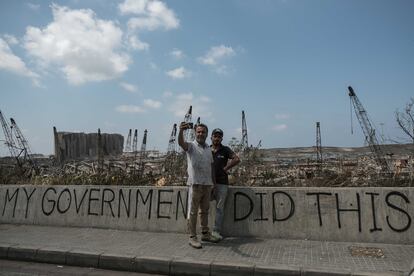 Dos libaneses el pasado mes de septiembre frente a los restos calcinados del puerto de Beirut donde se lee una pintada:'Mi Gobierno hizo esto'.