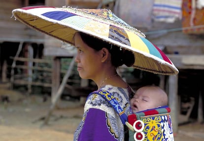 Una mujer lleva a su bebé a la espalda en Indonesia.
