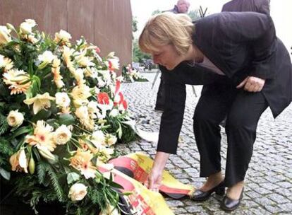 Angela Merkel coloca unas flores, ayer en Berlín, durante un homenaje a las víctimas del Muro.