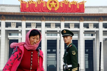 Un oficial de la policía paramilitar observa una mujer caminando por la plaza de Tianamen, en Pekín (China).