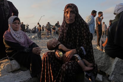 Somoud Wahdan mira a la cámara mientras está sentada con su hijo mientras espera que lleguen camiones con ayuda humanitaria, en la ciudad de Gaza, este viernes. 