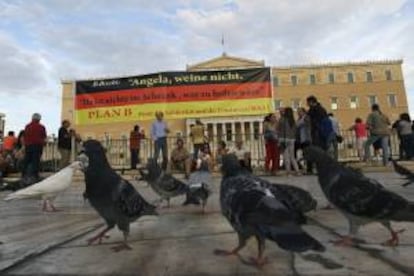 Varias personas con carteles revindicativos asisten a una manifestación celebrada ayer en frente del parlamento griego en Atenas, un día antes de la visita de Merkel al país.