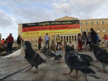 Varias personas con carteles revindicativos asisten a una manifestación celebrada ayer en frente del parlamento griego en Atenas, un día antes de la visita de Merkel al país.