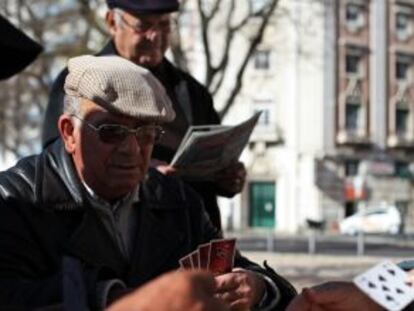 Aposentados portugueses jogam cartas em um parque de Lisboa.