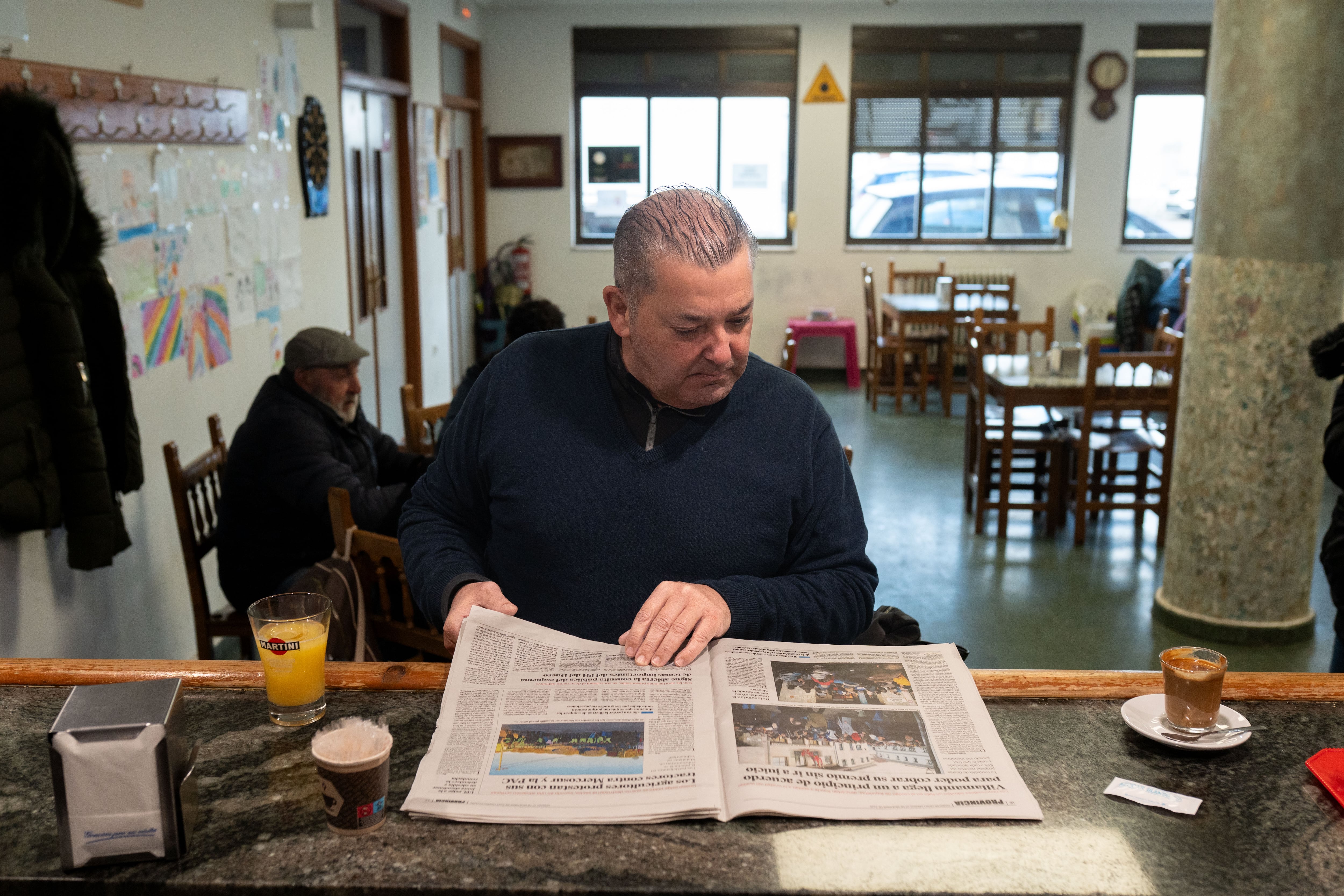 Un vecino de Villamanín lee un periódico local en el bar del pueblo.