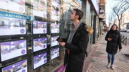 Un joven toma nota de pisos en venta en una inmobiliaria.