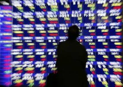 Un hombre observa un panel que muestra la información de la bolsa en Tokio.