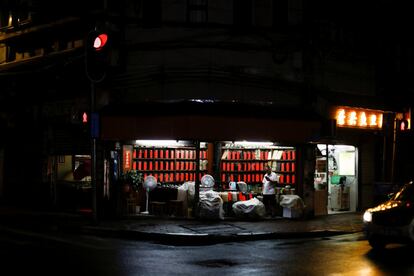 Por la noche, los puestos de vendedores ambulantes y las pequeñas salas de masajes iluminan los callejones oscuros que cobran vida con la charla y el consumo de cerveza mientras los amigos intentan combatir el sofocante calor del verano. En la imagen, un hombre se encuentra dentro de una tienda de té en el antiguo distrito de la ciudad de Liwan, en Guanghzou.