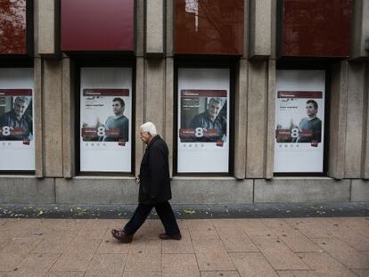 Un hombre camina ante los carteles de una sucursal del Banco Pastor.