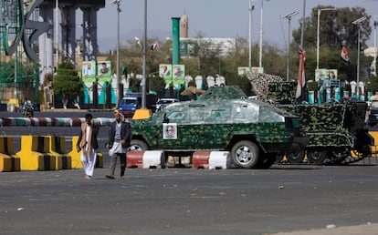 People pass two armored vehicles of the Houthis patroling at a street in Sana'a, Yemen, 07 December 2023