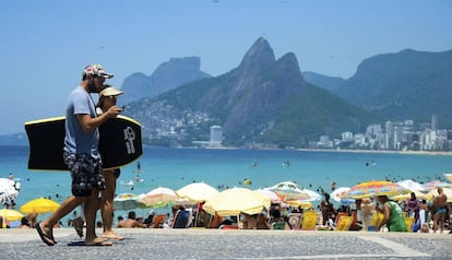 Casal caminha em praia do Rio de Janeiro.