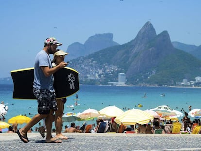 Casal caminha em praia do Rio de Janeiro.