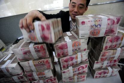 Un empleado de un banco en Hefei, en el centro de China, manipulando paquetes de billetes de yuanes 