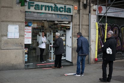 Una farmacéutica entrega los medicamentos a una clienta desde la puerta del establecimiento.